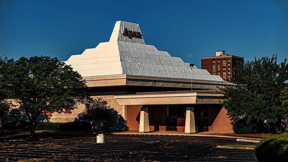 color photograph of the Apex department store in Pawtucket, RI. The 1960s era building has a distinctive white roof shaped like a ziggurat, or stepped pyramid.