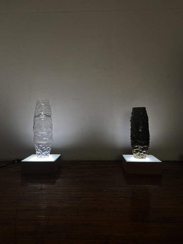 Corresponding towers of glass and ceramic atop glowing pedestals