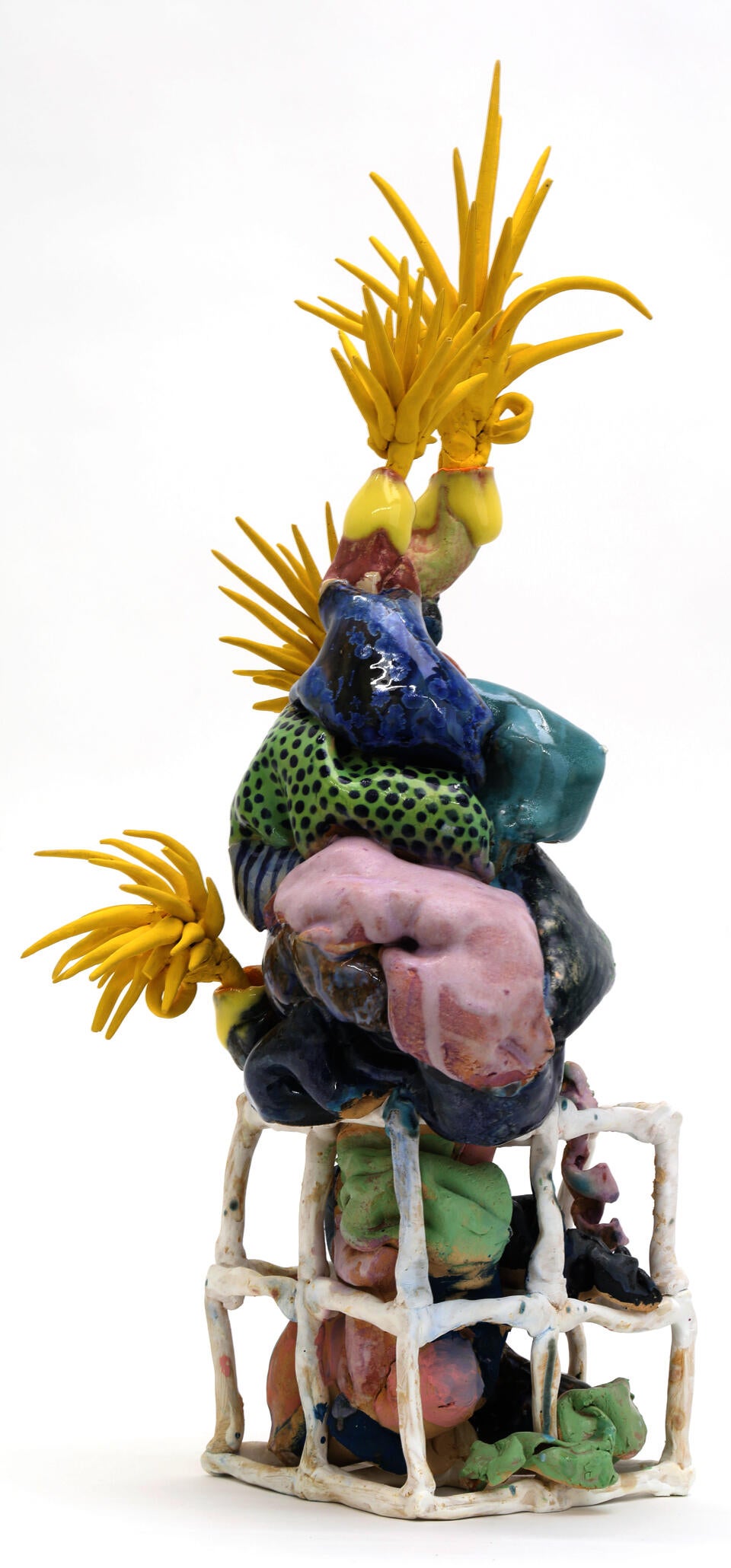 Squishy-looking multi-colored ceramic form rooting into square coil cubes with yellow spikey things on the ends. 