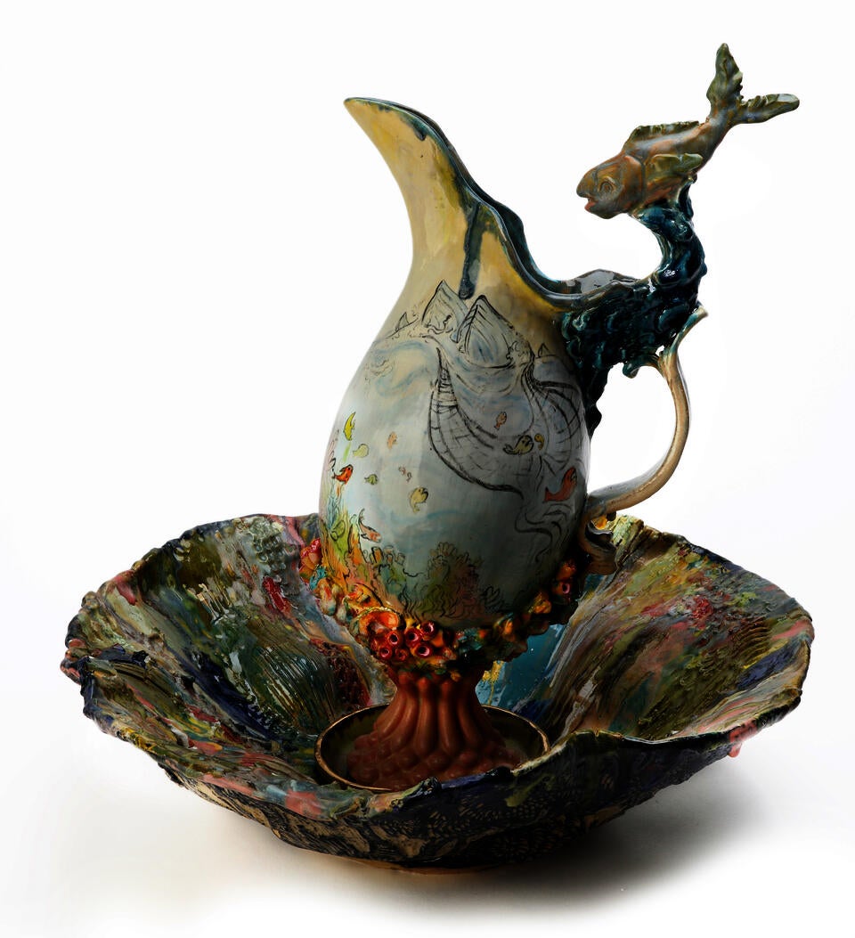 Pitcher and Basin set featuring a pitcher illustrated with fishing boats and a sculpted fish and a colorful basin interior with trees on the outside. 