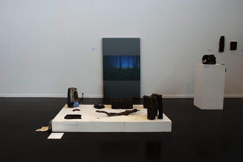 Installation view of ceramic tree trunks, and video of nest performance.