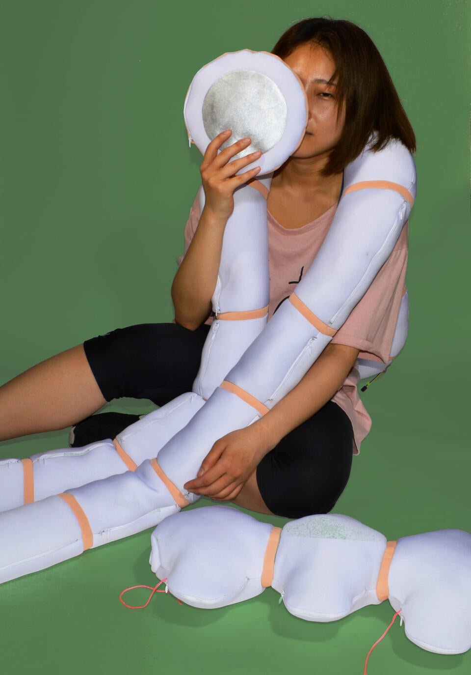 Color photograph, full body image with a girl holding the accessory of Nudo in green background