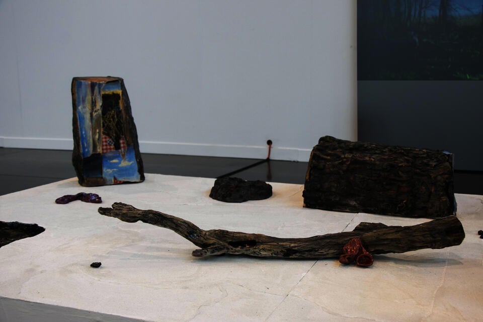 Installation view of ceramic tree trunks, and video of nest performance.