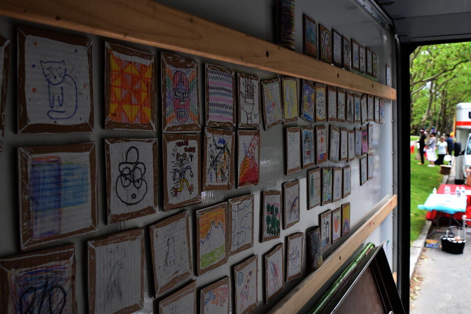 angled color photo of the interior of a Uhaul truck side; the surface is covered in small drawings done on cardboard