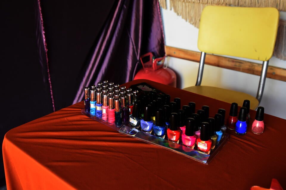 Close-up of a table and chair inside a U-haul with neatly organized nail polish in bright colors