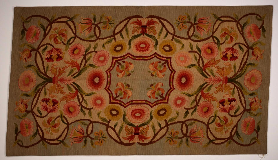 Floral design with scalloped rectangular center medallion. Vines with salmon-colored flowers twist around it. Palette includes tan, peach tones, green, and light blue.