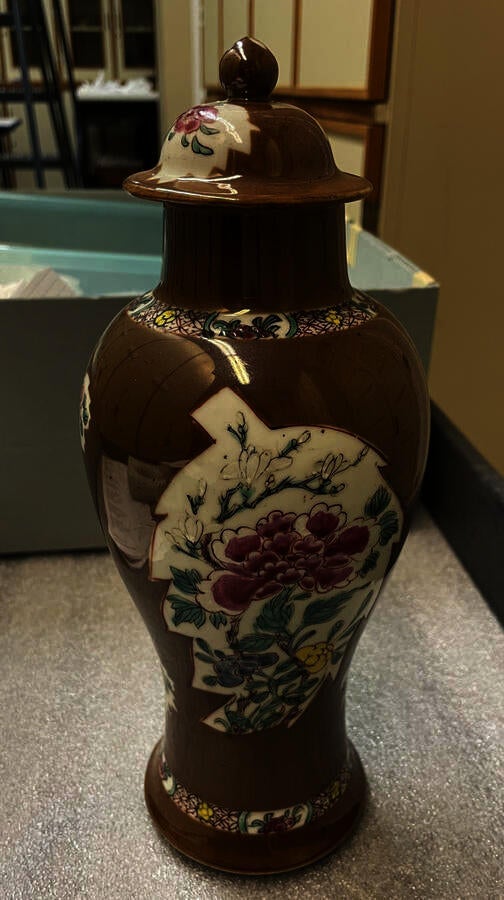 A brown and white porcelain covered vase with pink, green, blue, and yellow floral decorations. 