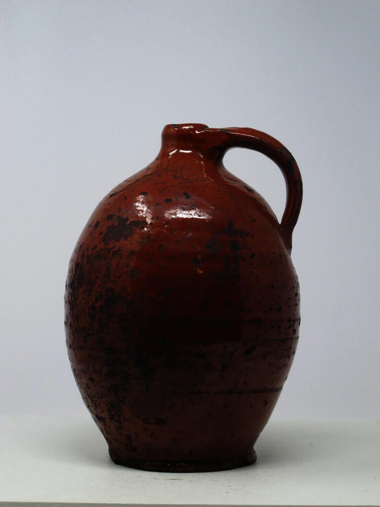A bulbous orange ceramic jug with a handle. 