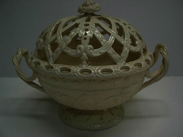 A creamware chestnut basket with sculptural woven handles, sculpted foot, and the lid has decorative cutouts. 