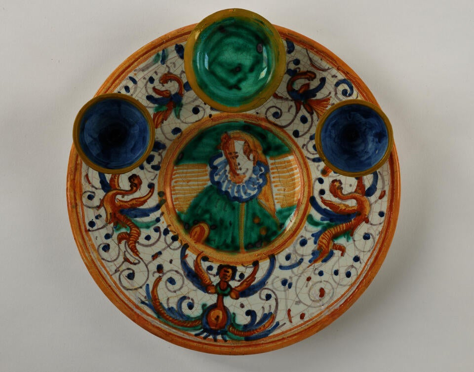  A lead-glazed earthenware plate that has different compartments. There are yellow, white, blue, and green glazed decorations.