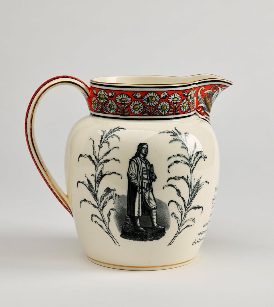 A  jug with a handle, lip, with red, yellow, and black daisy decorations, there is a prominent grey tone figure and flora on the body of the vessel.