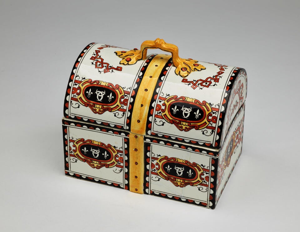 Container with a long, rectangular bottom and rounded top. White body with designs in black and brown. Yellow stripe down the center and yellow handle on top.