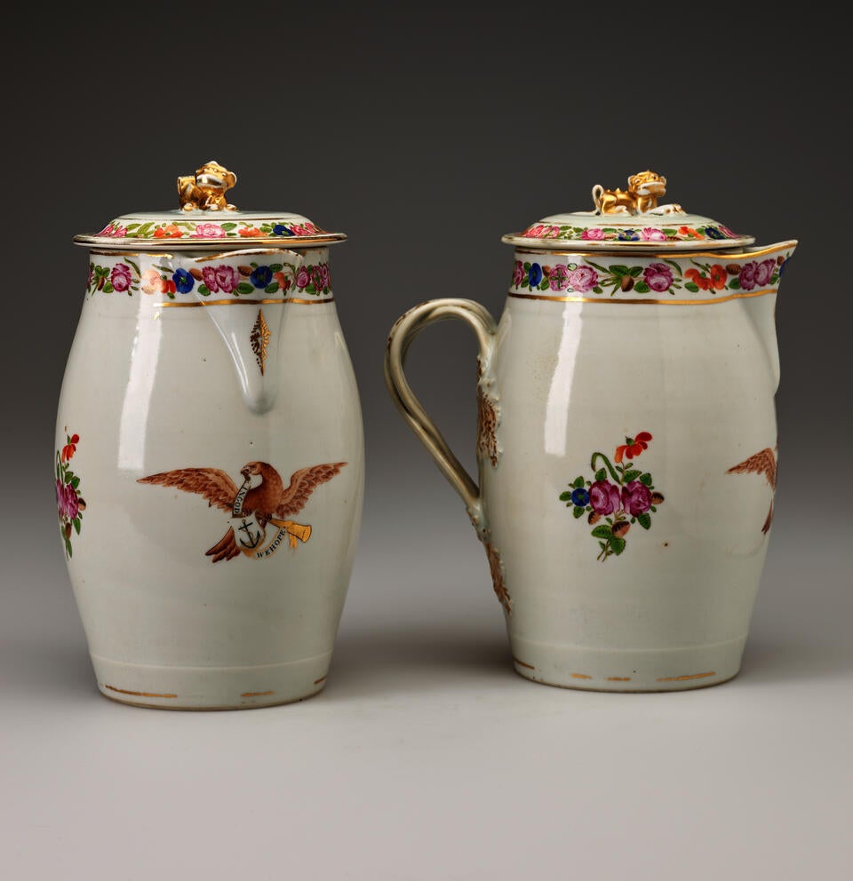 Two cream colored lidded vessels with decorations of flowers and eagles. 