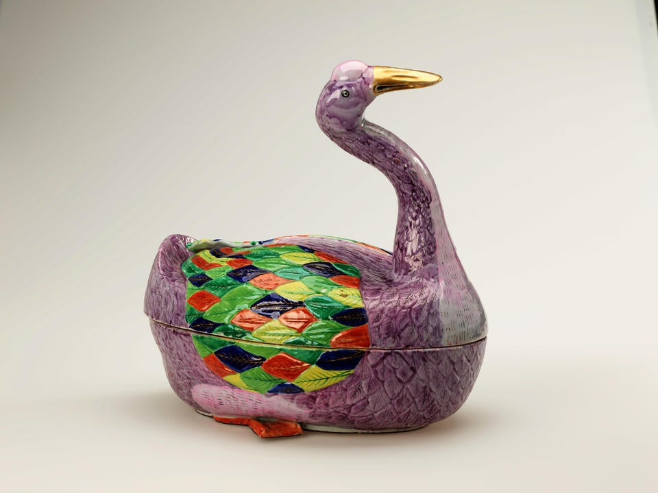 A sculptural vessel in the shape of a goose. The purple body is accented with diamond-shaped decorations in green, blue, yellow, and orange.