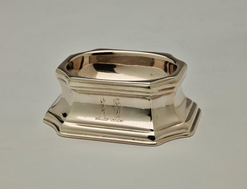  A silver salt container that is rounded on the inside and angular on the outside. 