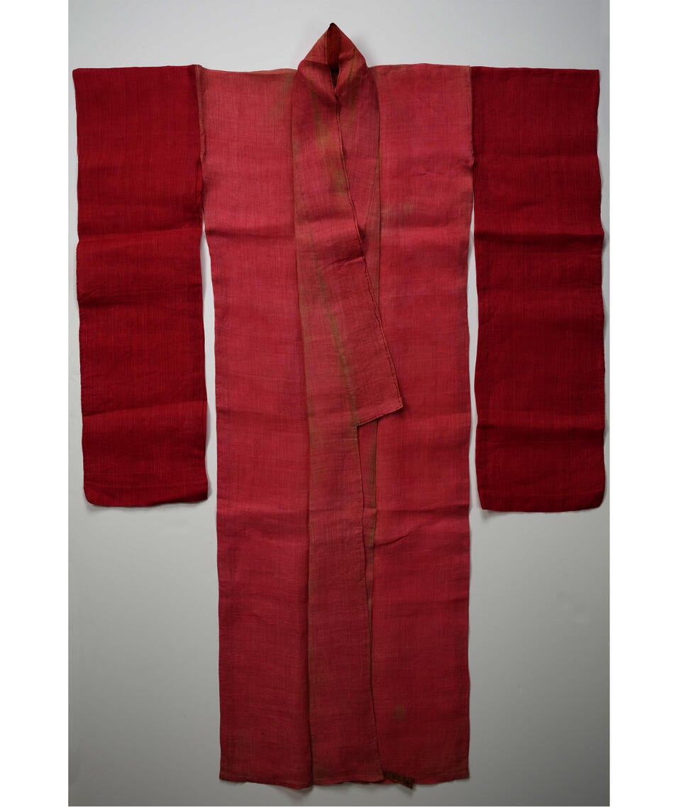 A pink kimono with an open orange collar. Laid flat, the shoulders of the kimono are squared off.