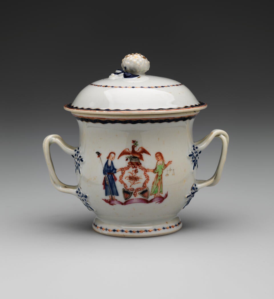 A white vessel with two symmetrical handles with blue decorations, heraldry imagery, two figures with light hair. One holding a staff and the other is blindfold and holding scales.