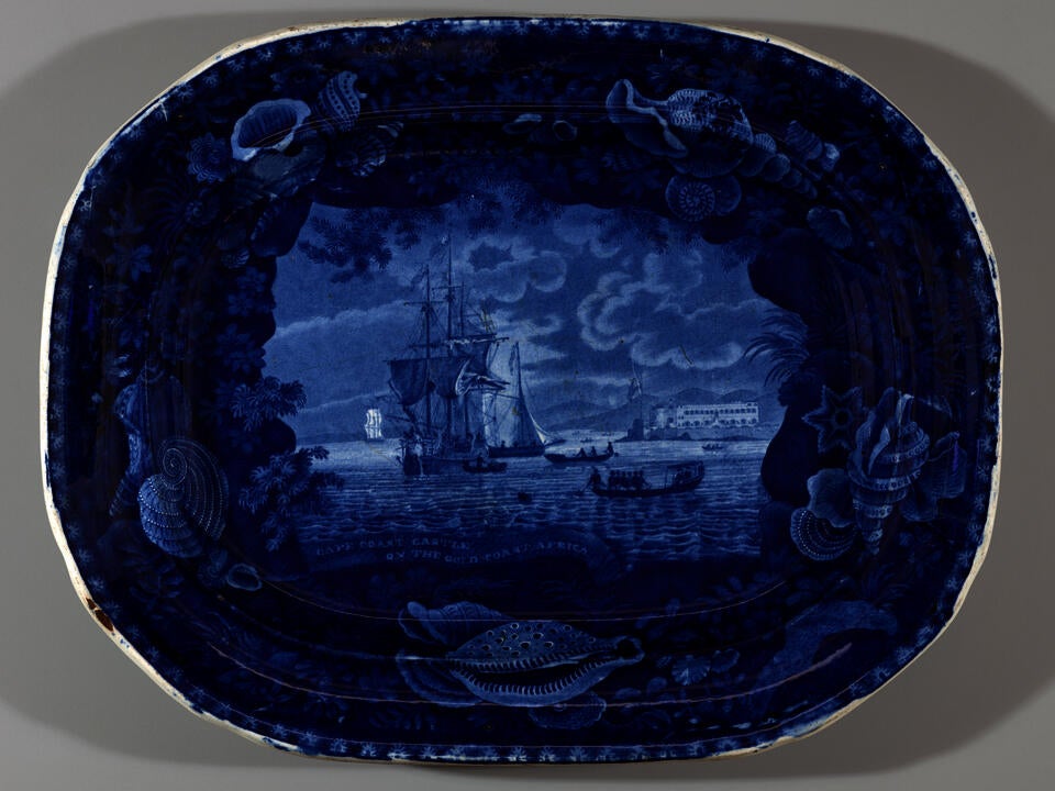 A transfer-printed earthenware platter with dark blue decorations depicting a coastal scene.