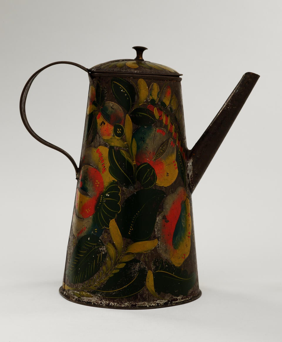 A tin coffee pot with painted orange, yellow, and green floral decorations.