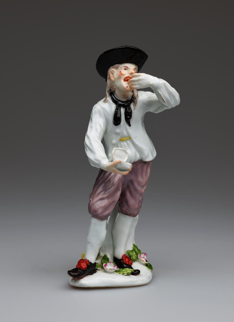 A figure dressed in historical clothing, holding a box in one hand and consuming something from the other hand.