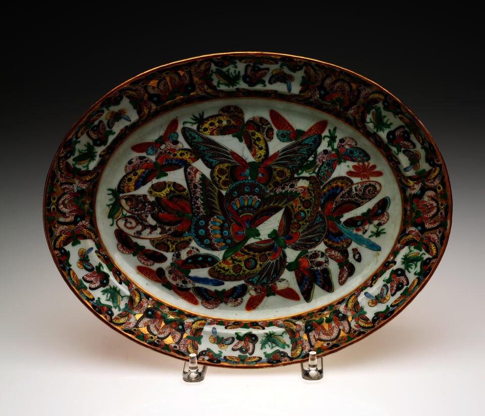  An oval serving dish. Decorated in the center with multicolored butterflies. 