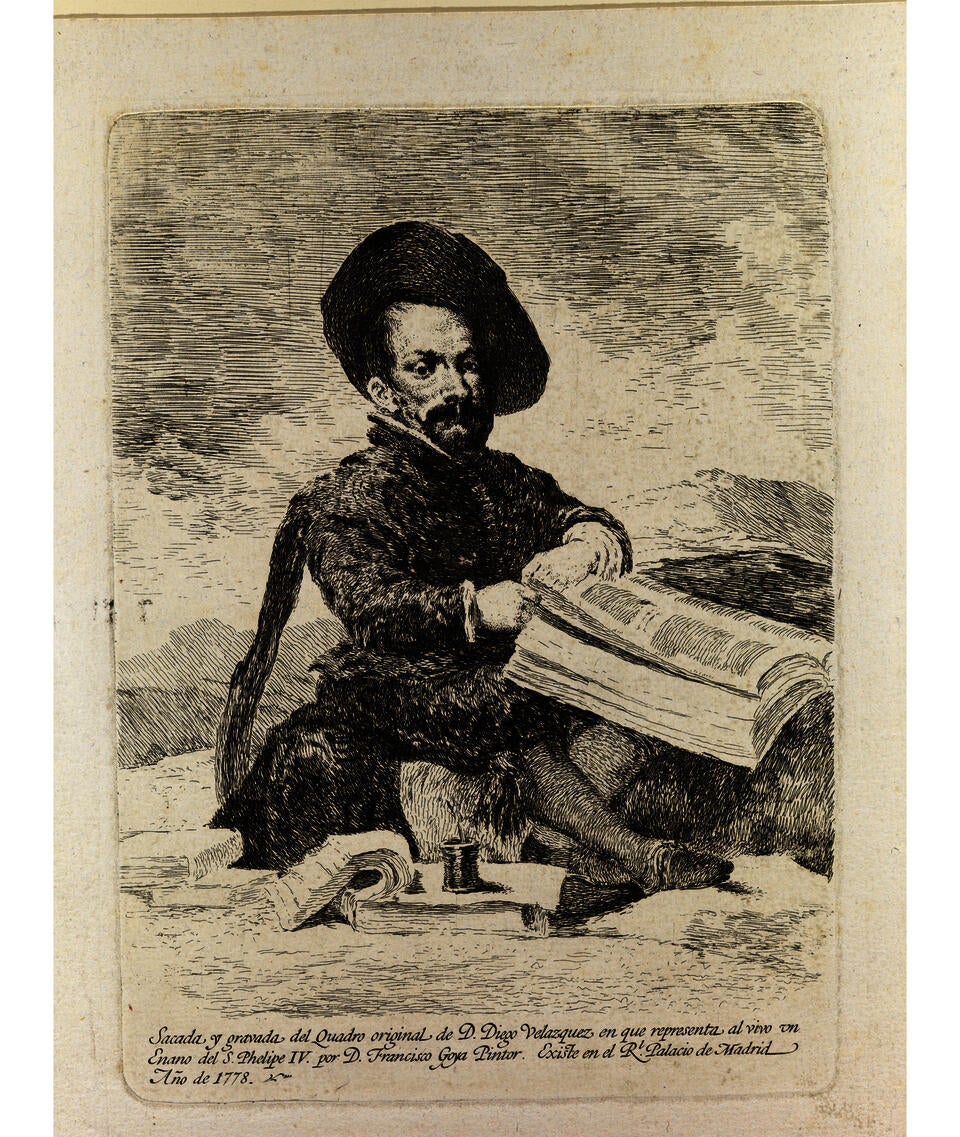 In an etching on beige paper, a little person sits cross-legged among books, papers, and a pot of ink. He wears an 18th-century suit and wide-brimmed hat. Text at the bottom is in Spanish. Translated into English reads: “Taken and captured from the original painting of Diego Velazquez which represents the Dwarf of King Philip IV by Francisco Goya, [illegible] in the Royal Palace of Madrid, 1773.”