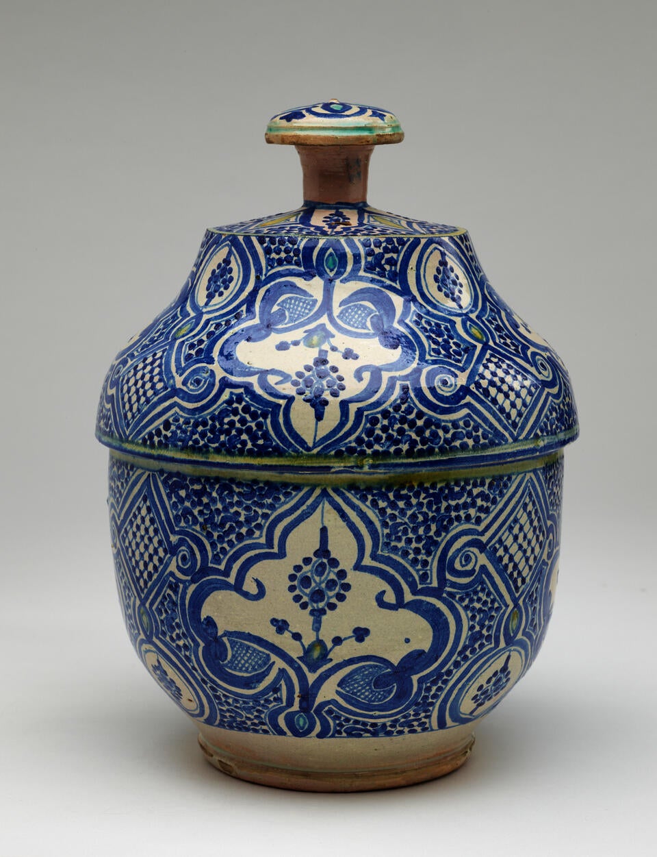 A gray-white lidded bowl with delicate blue symmetrical decorations and a finial with turquoise decorations.