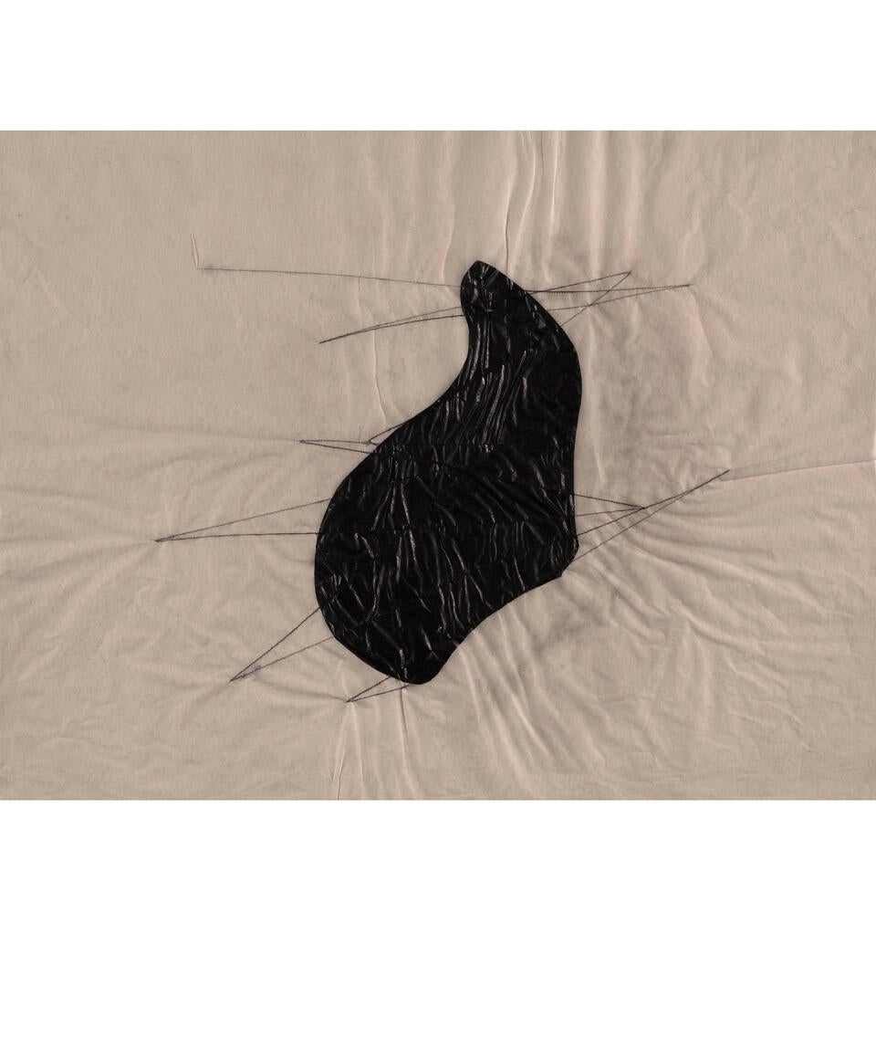 A black, curved abstract shape lies at the center of a piece of wrinkled tissue paper. Zig-zagging lines of thread intersect over and beyond the shape.