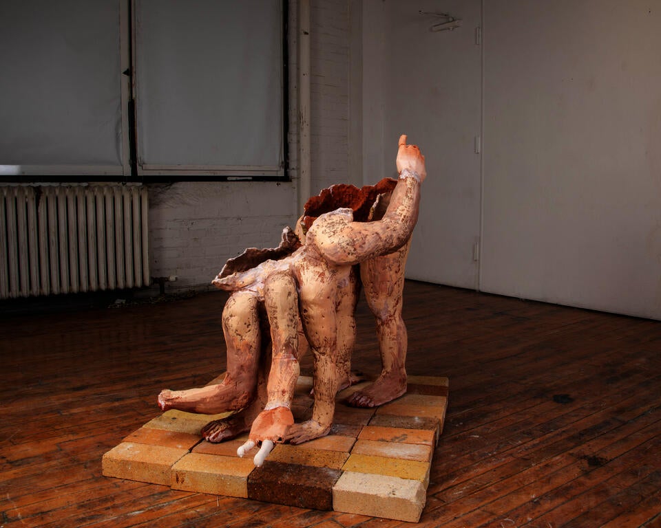A large, multi-limbed terracotta figure stands on all fours upon bricks