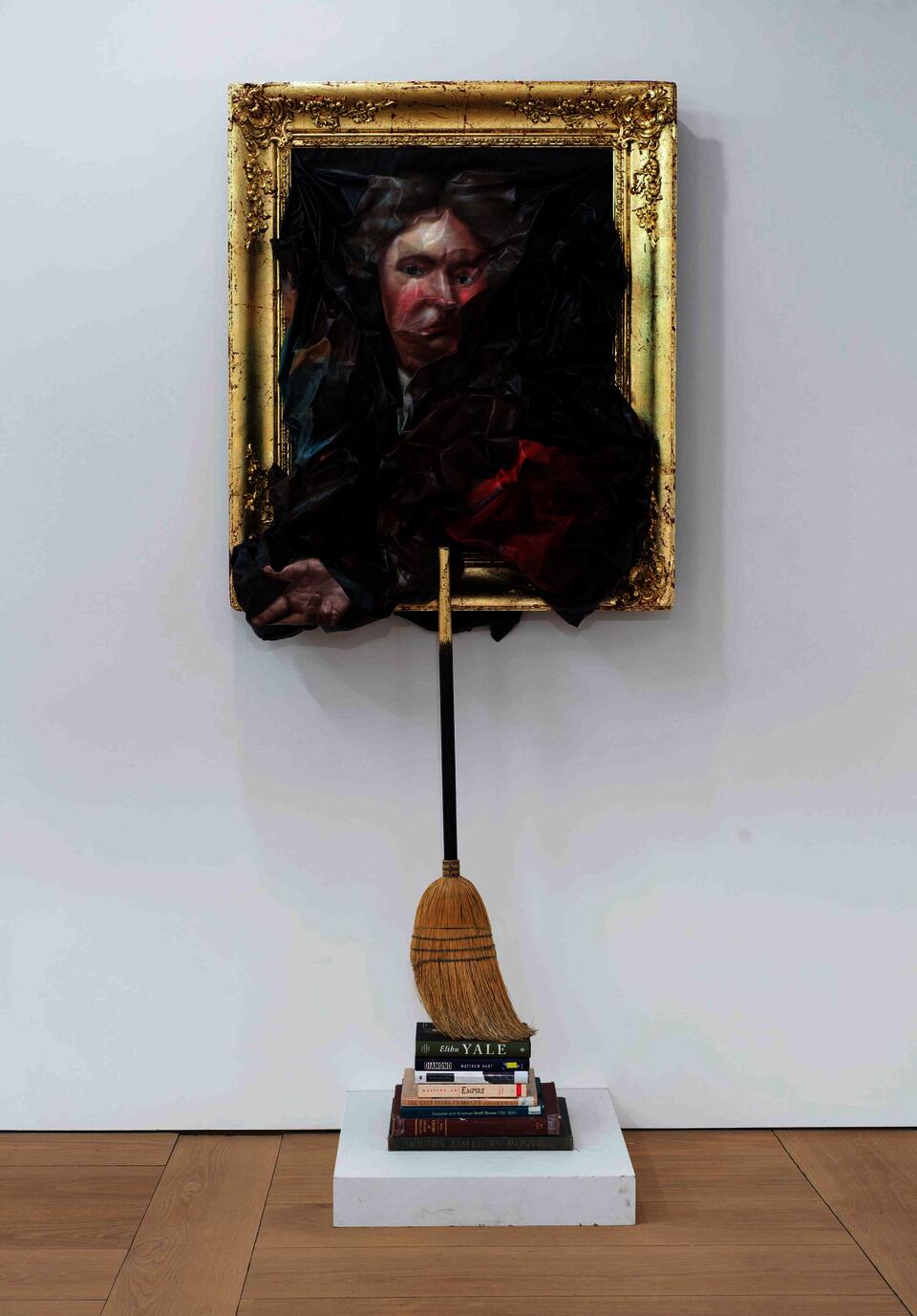 Titus Kaphar's work Unfit Frame features a wrinkled and disfigured canvas of Elihu Yale of Yale University, whereas below the painting is a stack of books which emphasize Yale's history and fortune. The books prop up a straw broom which leans against the frame of the canvas above. 