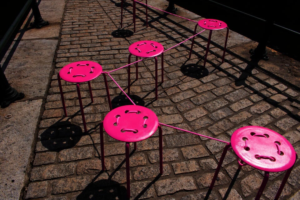 An image showing bright pink chairs tied together.