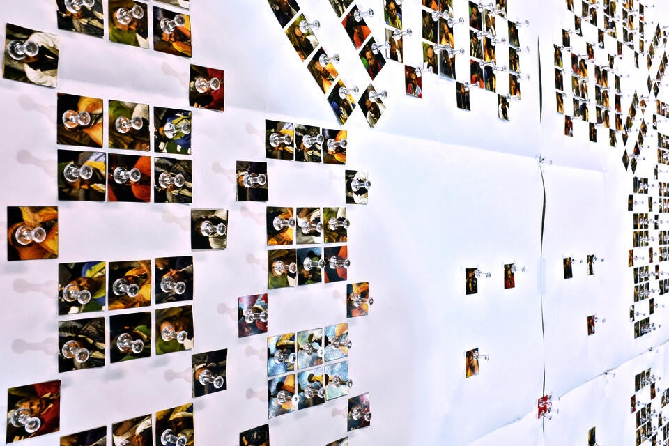 This image shows an installation of numerous paper cutouts pinned on the wall.