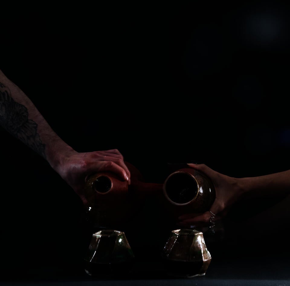 2 people collaborating on serving liquid from a pitcher
