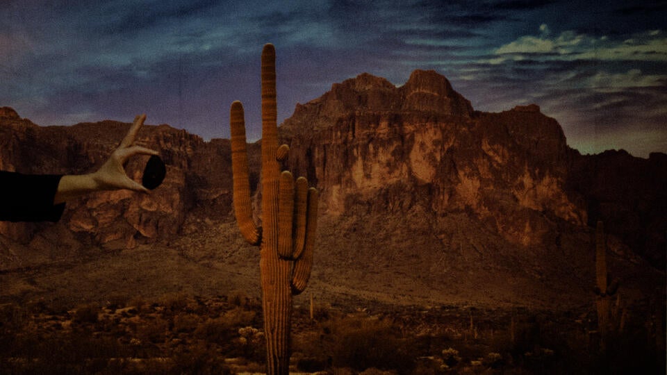 A western background with a hand holding a piece of coal. 