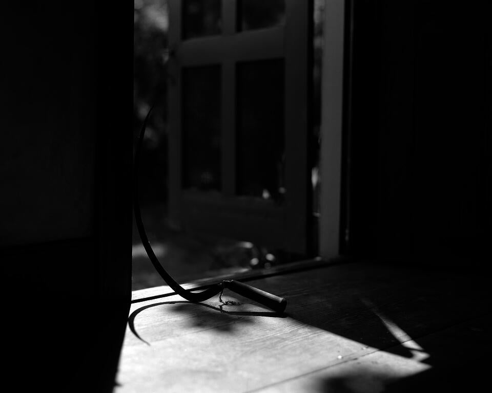 Grayscale photograph of a sickle inside of a door way. 