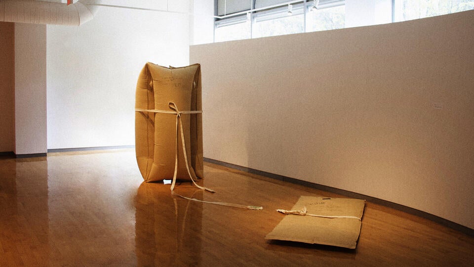Three large inflated brown tone bag held by a fabric belt on the left side, One deflated bag on the right side.
