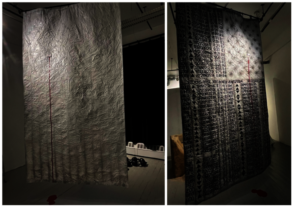 Gone But Not Forgotten? is a 10-foot-tall painted all-white United States flag that is hung up vertically to the ceiling and freely draping down. There's a visible bullet hole stain on both sides. And a dark red bloodline flows down from it, making a red puddle on the floor.
