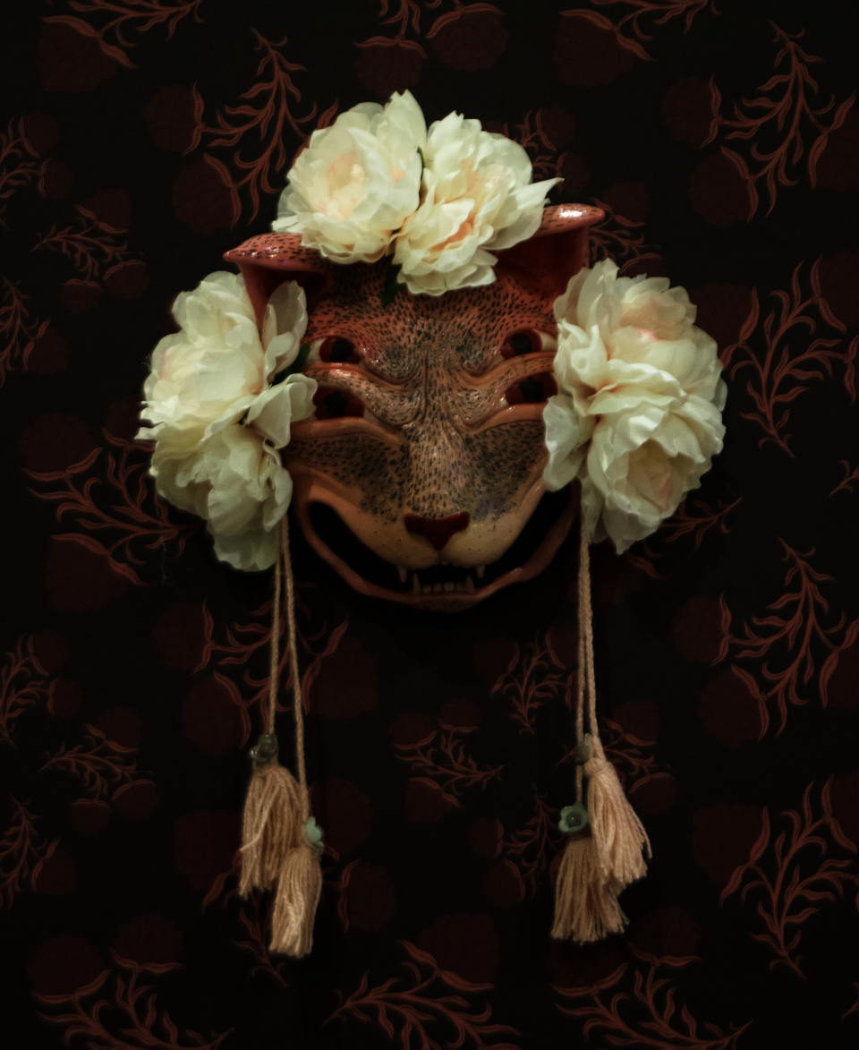 Pink ceramic mask of yowling cat with four eyes.