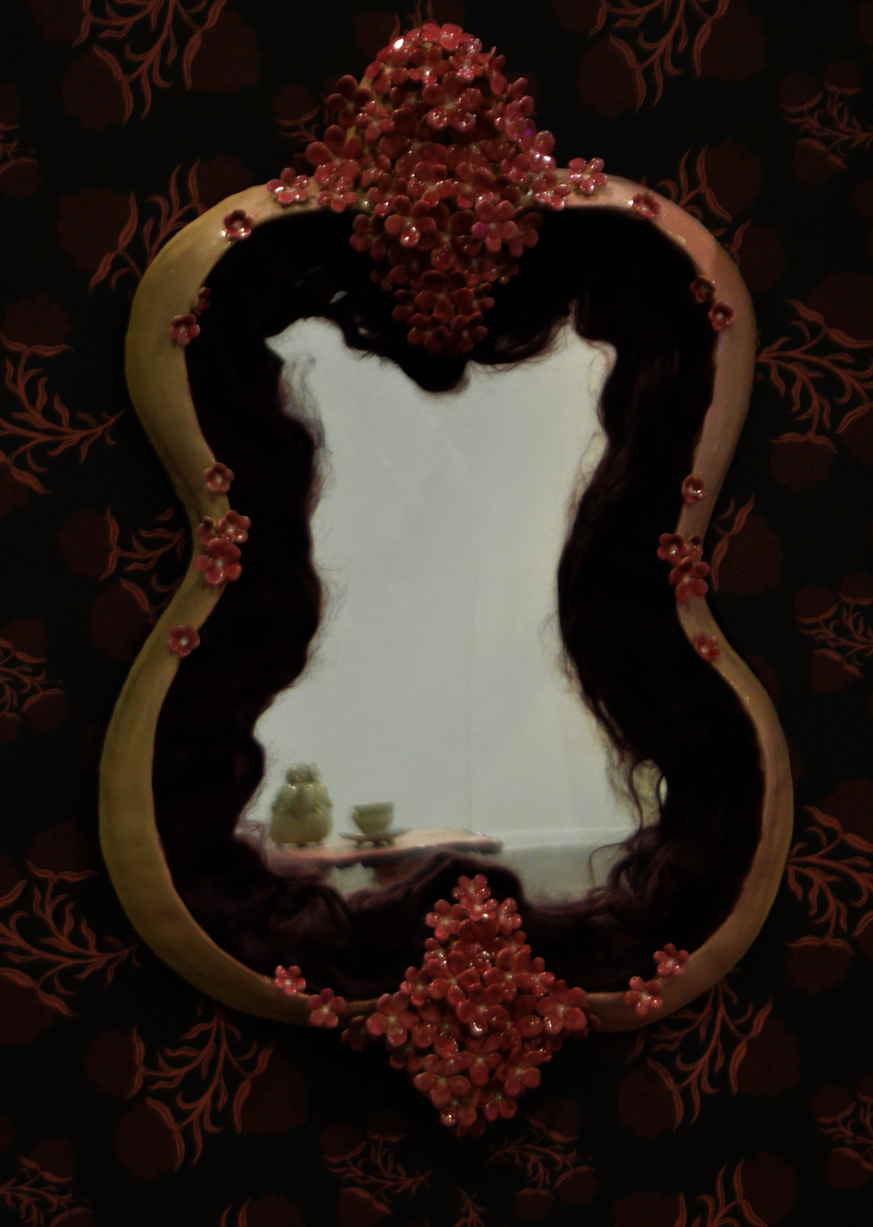 Pink flower ceramic frame around funhouse mirror.