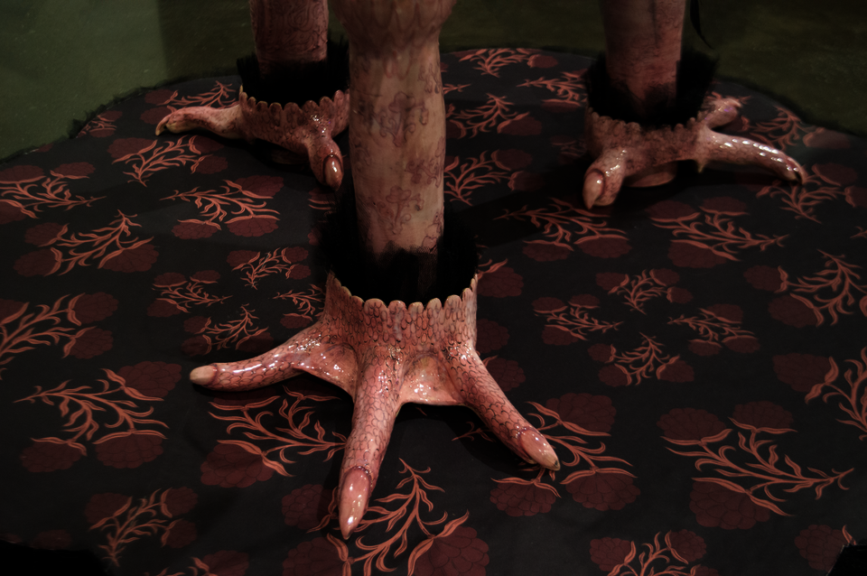 Pink ceramic chicken feet at the base of a ceramic chair.