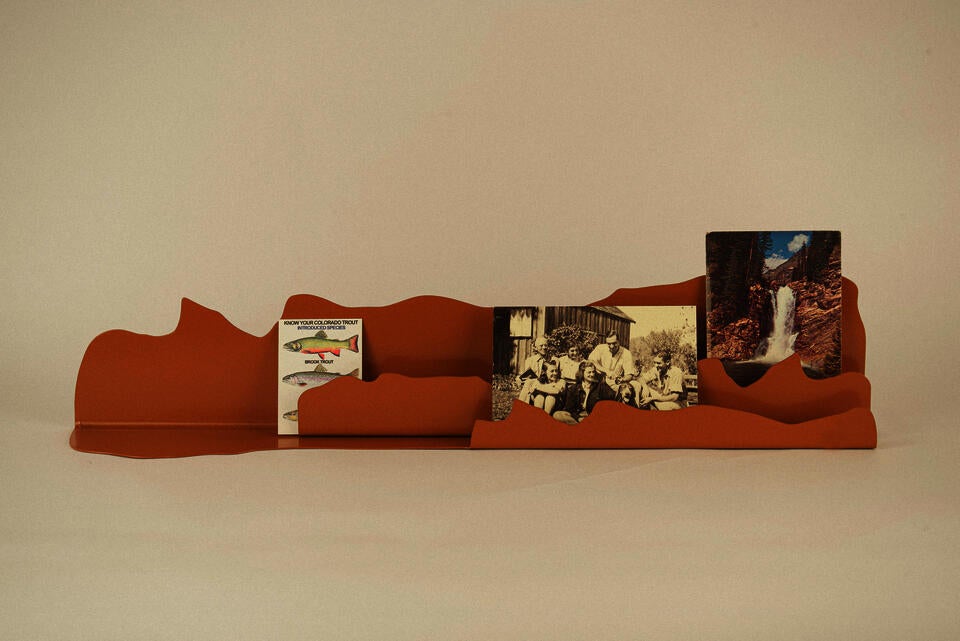 One burnt orange color steel shelf, showcasing three postcards.
