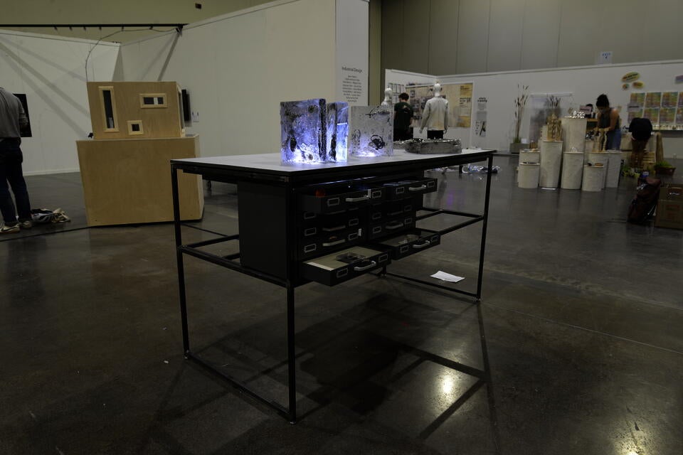 Thin metal standing-height desk with multiple drawers open. Glass books adorn the top of the table.