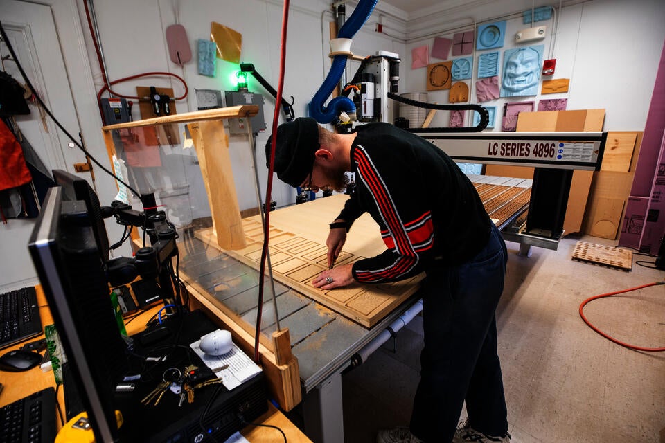 Student pulls out pieces of MDF cut by a large CNC machine.