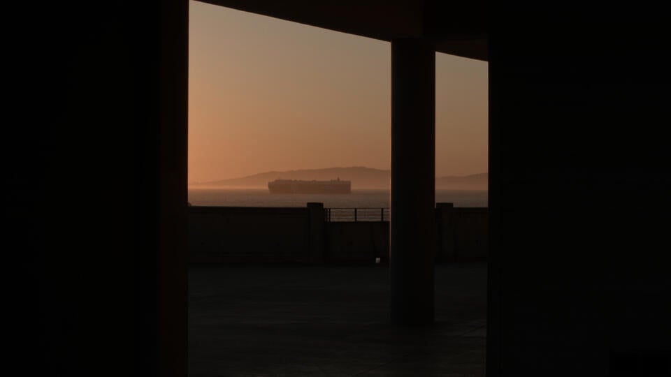 A cargo ship appears on the distant horizon