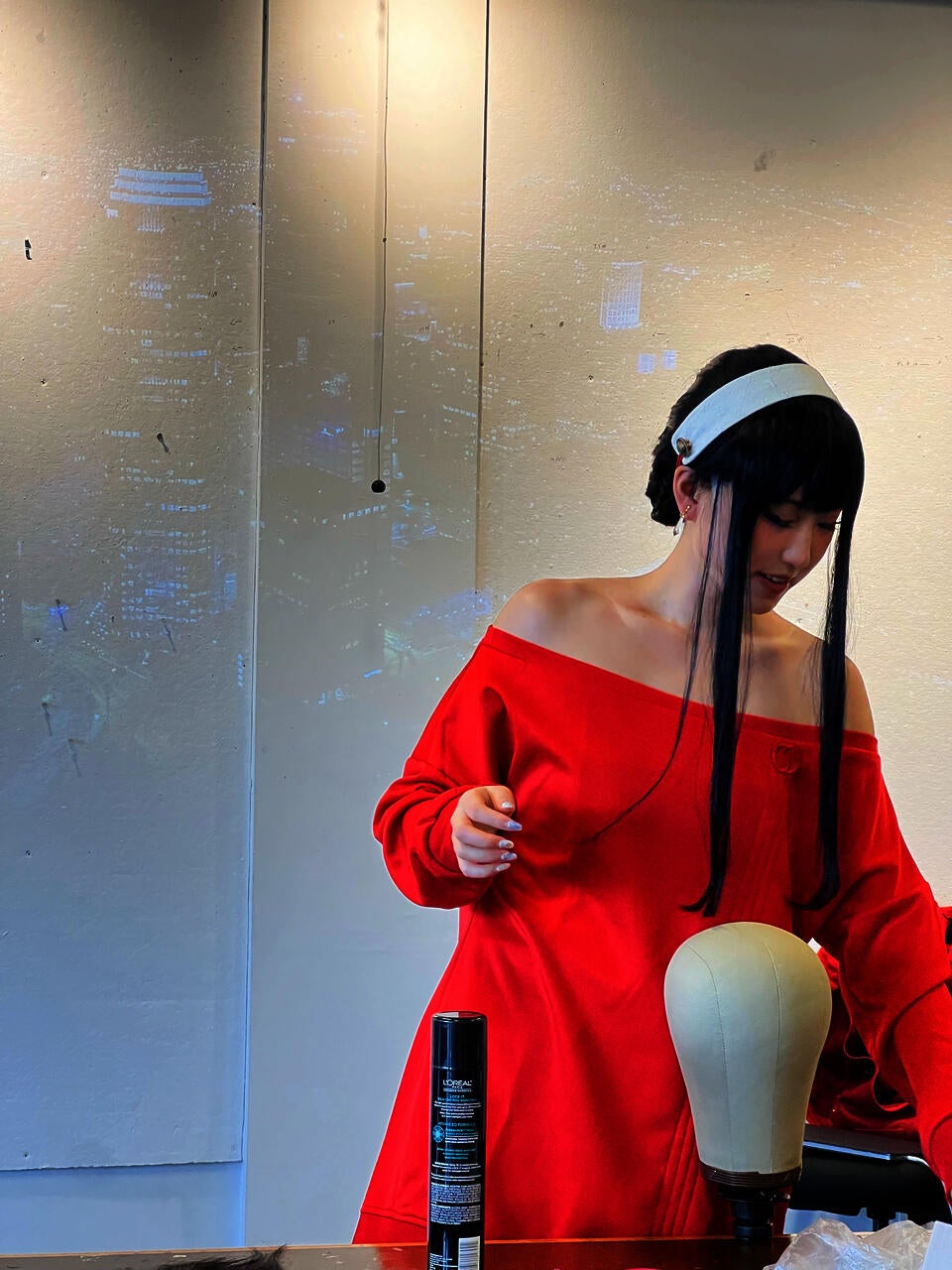 The author dressed as Yor Forger, a female character from the Japanese anime and manga series Spy × Family, doing a demo on wig styling in class.