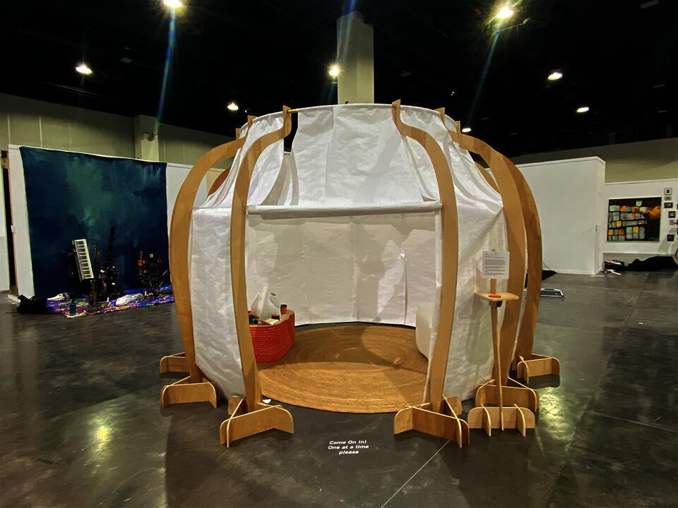 A large temporary wood and tyvek structure stands in a large convention center