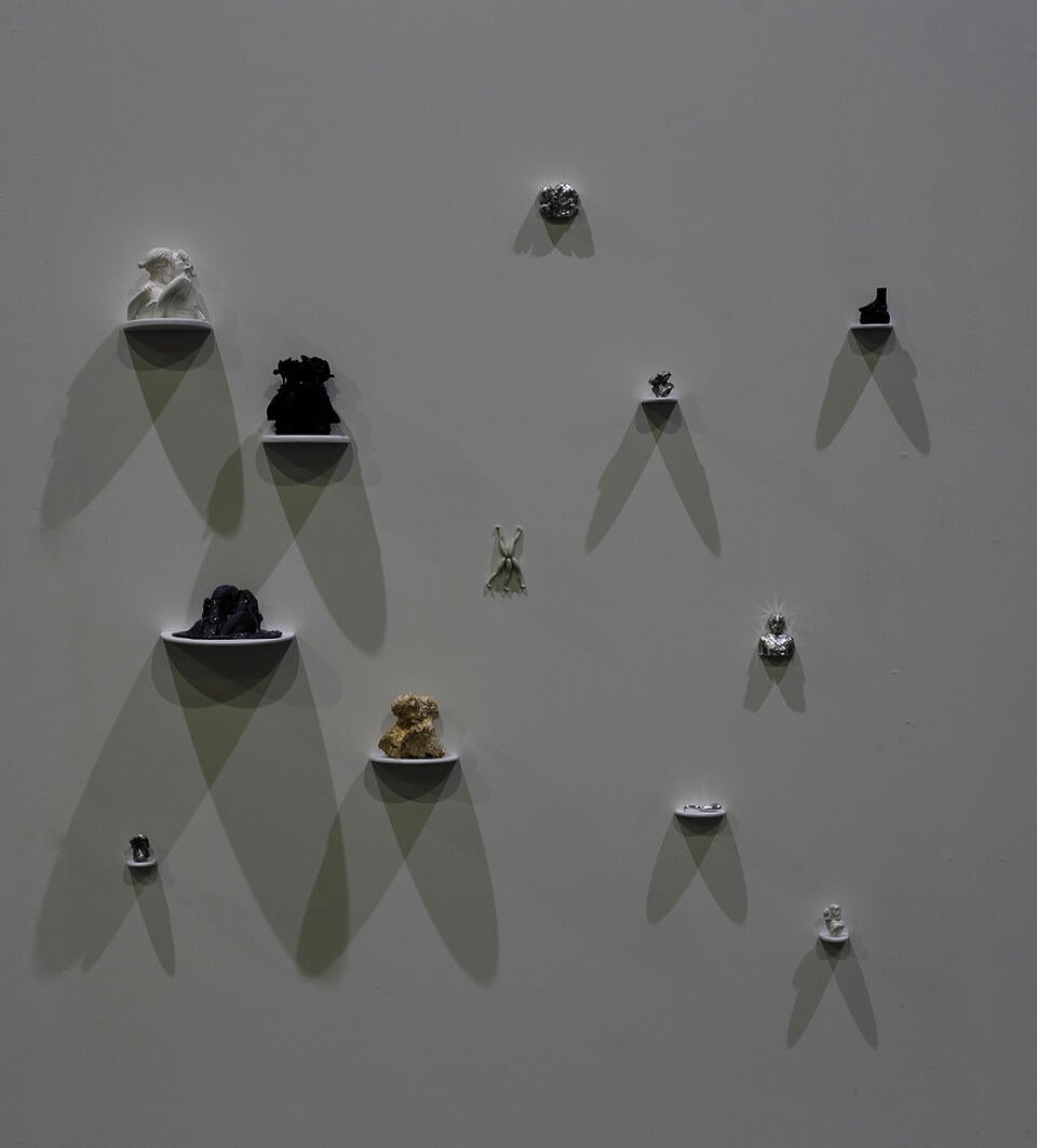 A grouping of sculptures of various materials sitting on individual shelves