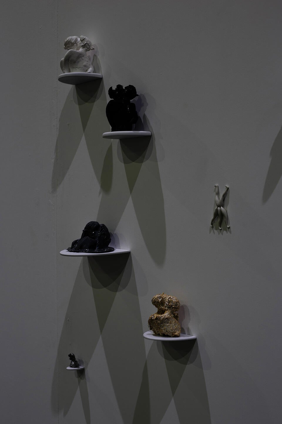 A grouping of sculptures of various materials sitting on individual shelves