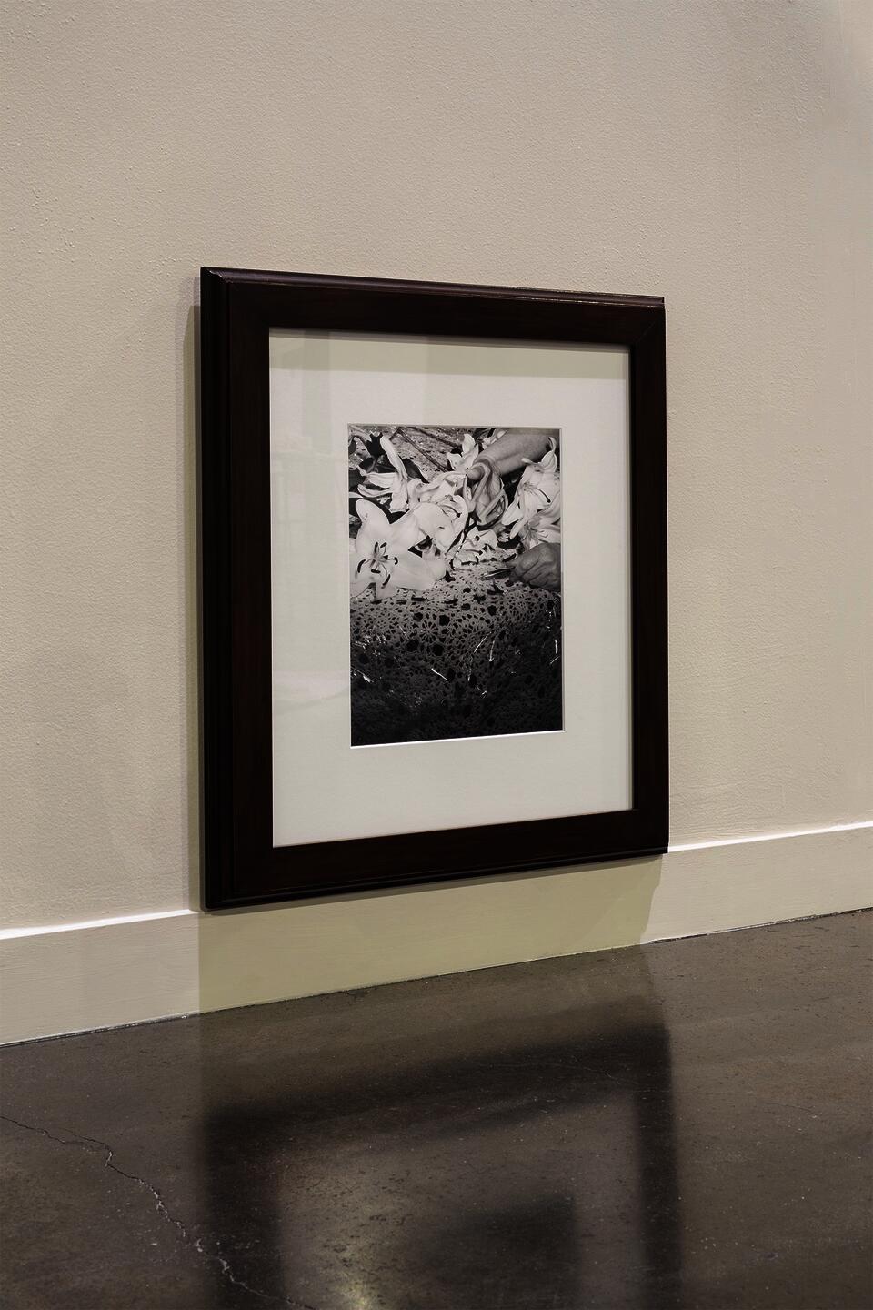 Framed black and white photograph of lilies on a table.
