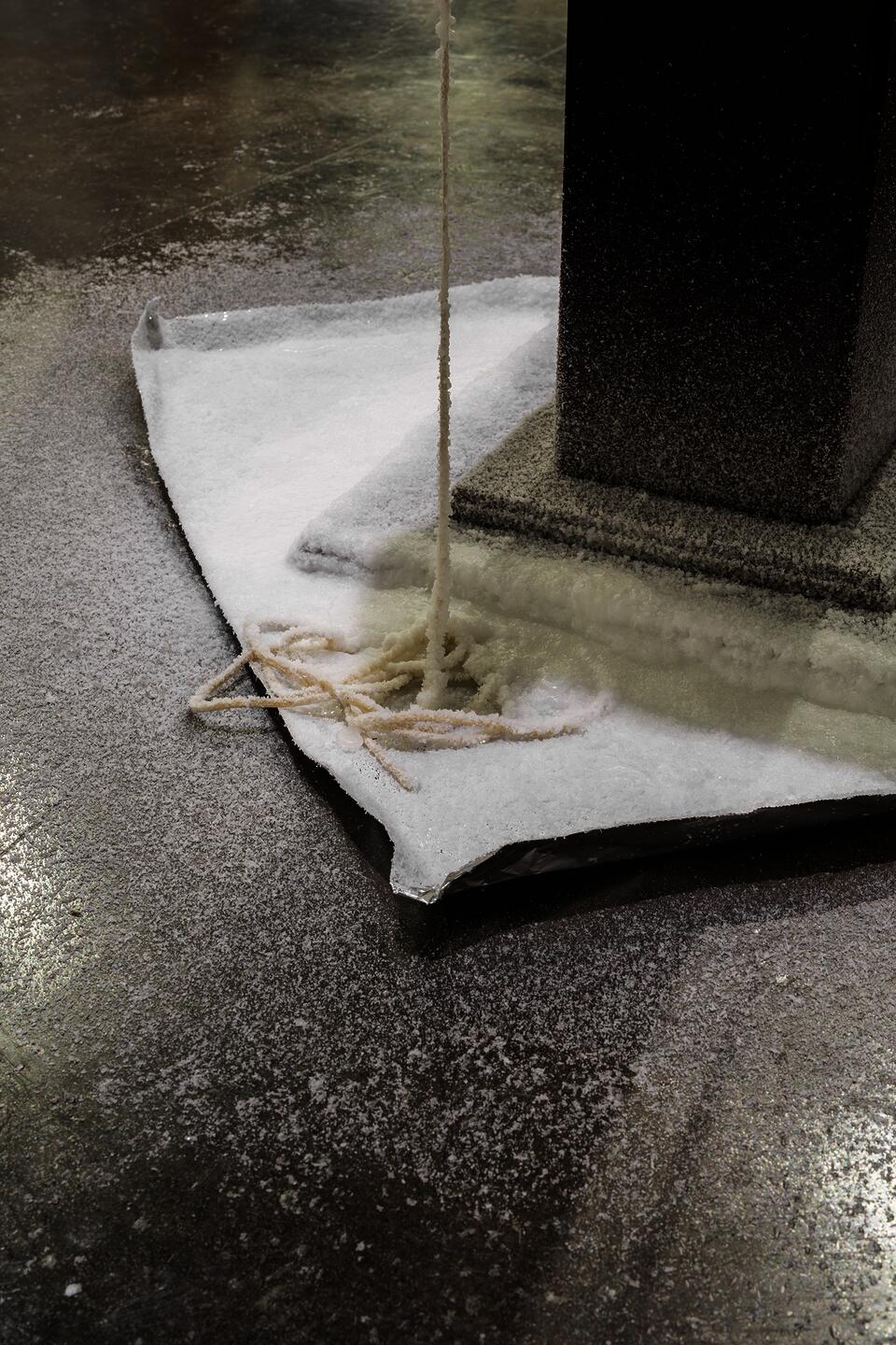Wax sculpture on wooden podium with wax dripping from figures.